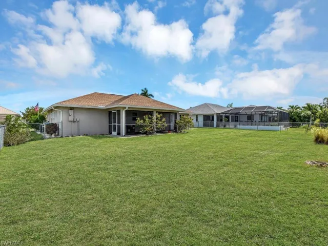 Expansive green lawn with a chain-link fence, offering open-air space