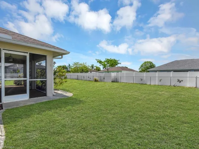 Expansive green lawn with a white vinyl fence and chain-link fence combination