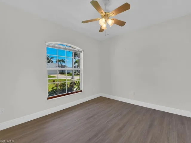Room with wood-finish flooring, white baseboards, and light gray walls