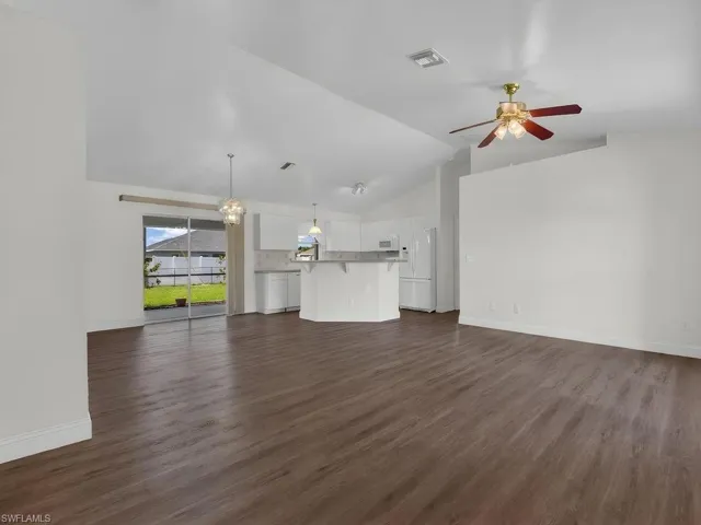 Open concept living space featuring wood-finish flooring, vaulted ceilings, and a ceiling fan