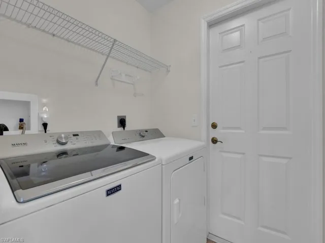Dedicated laundry area featuring a white paneled door, wall-mounted wire shelving, and a built-in utility box