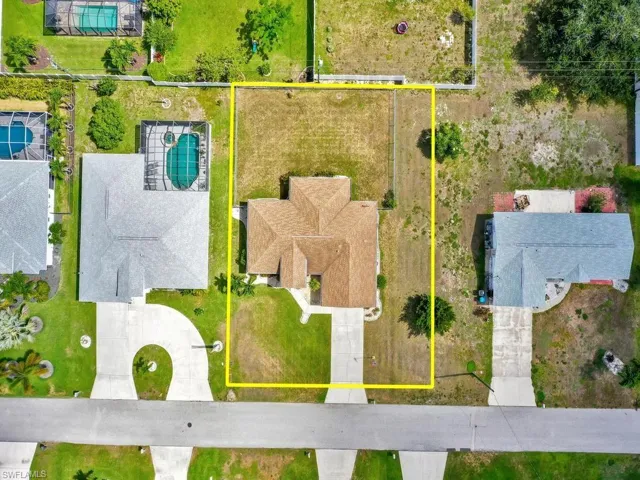 Expansive lot featuring a single-story residence with a hip roof, mature landscaping, and a concrete driveway