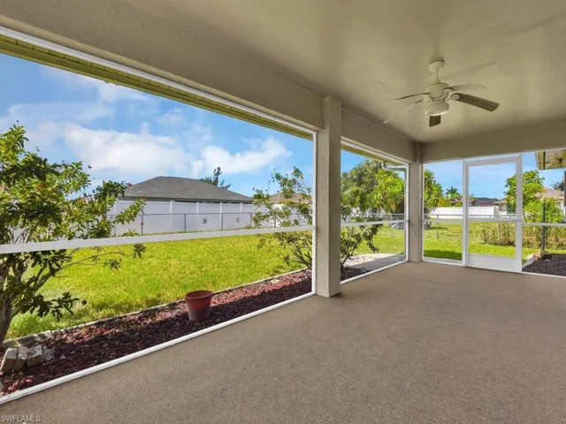 Screened outdoor patio featuring a textured concrete floor, ceiling fan, and direct access to the backyard