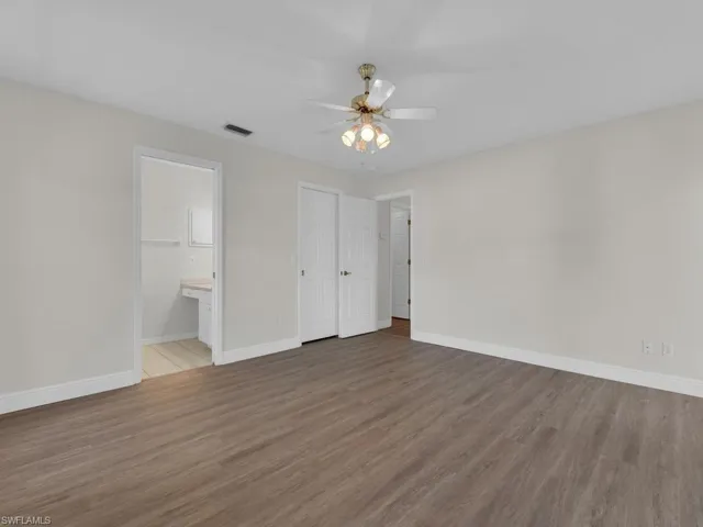 Spacious room featuring wood-finish flooring, light gray walls, and white baseboards