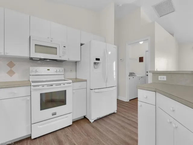 Kitchen featuring white cabinetry, light-toned countertops, a white electric range, and a white refrigerator