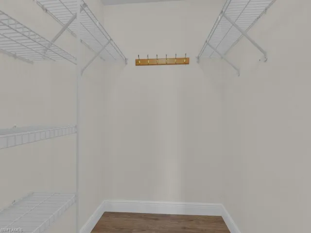 Walk-in closet featuring wire shelving, wall-mounted coat hooks, white baseboards, and wood-finish flooring