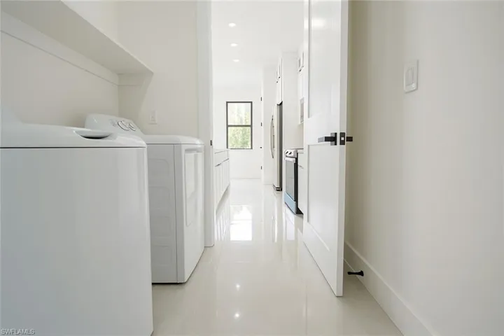 Laundry area with light tile patterned floors, washing machine and dryer, and recessed lighting