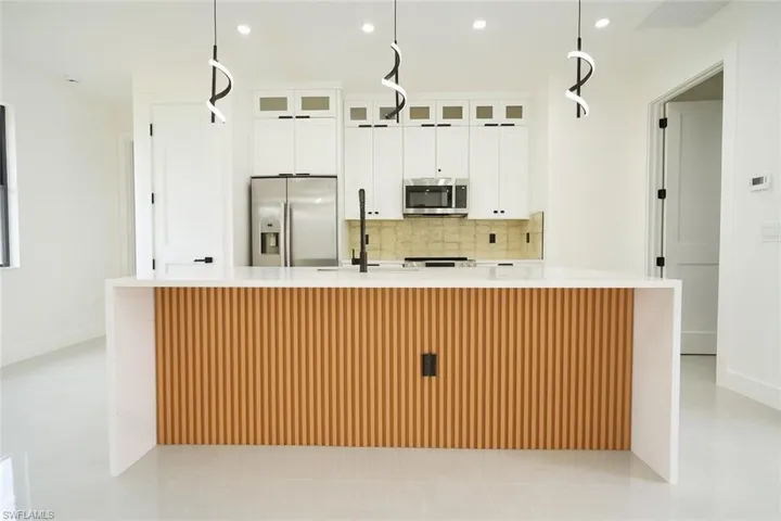 Kitchen with recessed lighting, pendant lighting, backsplash, appliances with stainless steel finishes, and white cabinetry