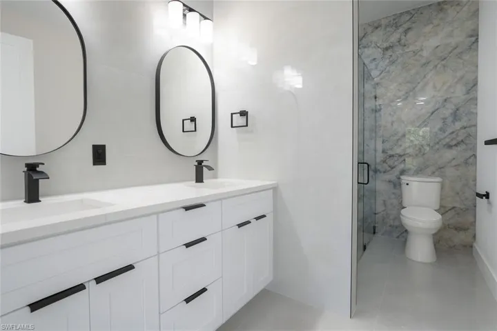 Full bathroom with tile walls, double vanity, a shower stall, and light tile patterned floors