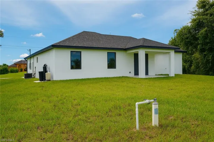 Back of property featuring stucco siding, a lawn, a patio, and a shingled roof