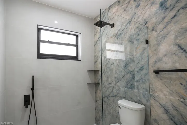 Full bath featuring tiled shower and tile walls