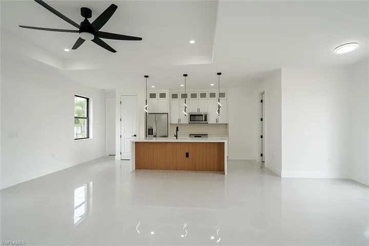 Kitchen with glass insert cabinets, a kitchen island with sink, open floor plan, decorative light fixtures, and white cabinets