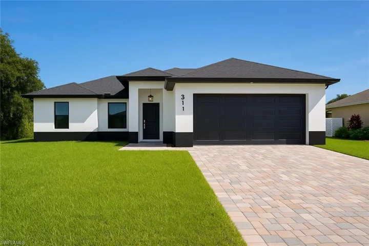 Prairie-style house with a front lawn, decorative driveway, stucco siding, and an attached garage