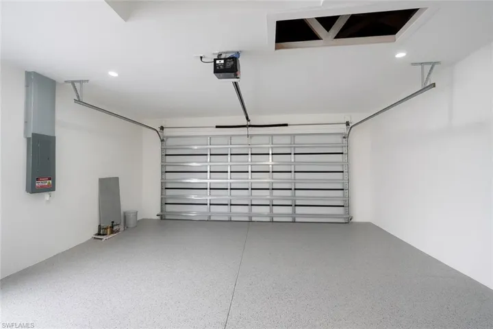 Garage featuring electric panel, recessed lighting, and a garage door opener