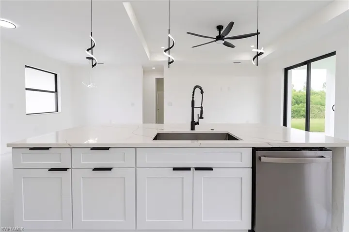 Kitchen featuring plenty of natural light, a large island with sink, dishwasher, pendant lighting, and recessed lighting