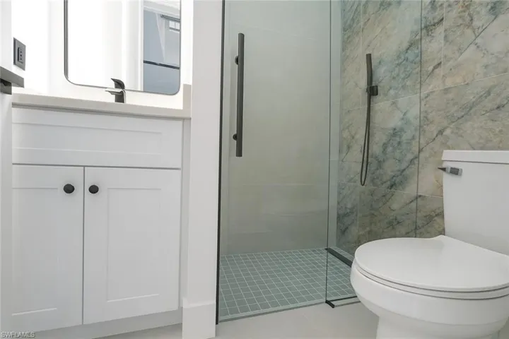 Full bath with vanity, a shower stall, light tile patterned flooring, and tile walls