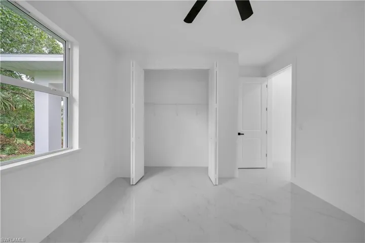 Unfurnished bedroom with light marble finish floors, a closet, and ceiling fan