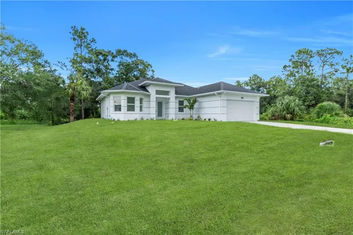 Prairie-style home featuring a front yard, an attached garage, driveway, and a shingled roof