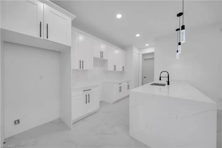 Kitchen with white cabinets, light stone countertops, recessed lighting, hanging light fixtures, and a peninsula