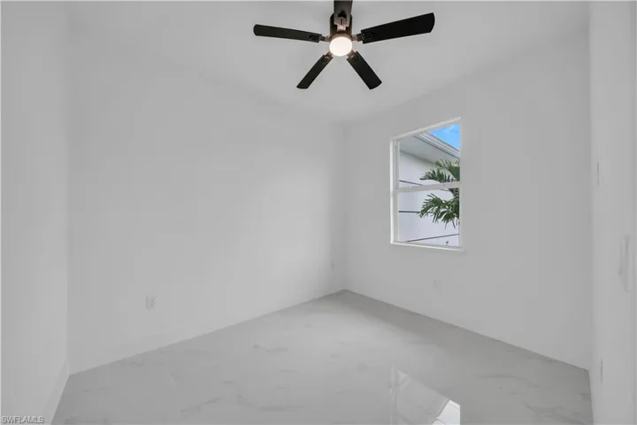 Empty room with light marble finish floors and ceiling fan