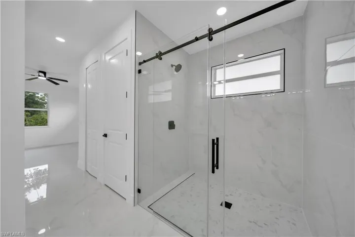 Full bathroom featuring plenty of natural light, marble tiled flooring, a marble finish shower, recessed lighting, and ceiling fan