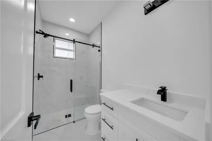 Full bathroom featuring vanity, a marble finish shower, and recessed lighting