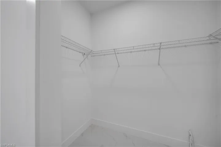 Walk in closet featuring light marble finish flooring
