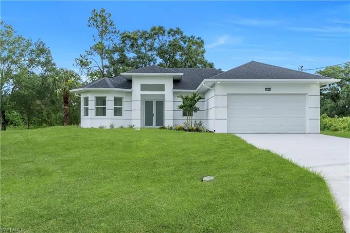Prairie-style house featuring a front lawn, a shingled roof, a garage, concrete driveway, and stucco siding
