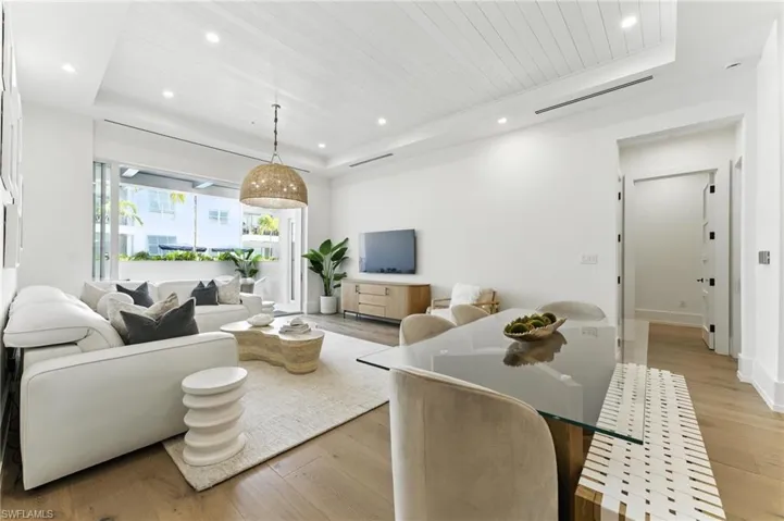 Living area with a raised ceiling, light wood-style floors, recessed lighting, and wooden ceiling