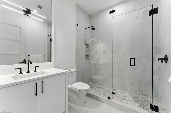 Bathroom with marble finish flooring, vanity, and a marble finish shower