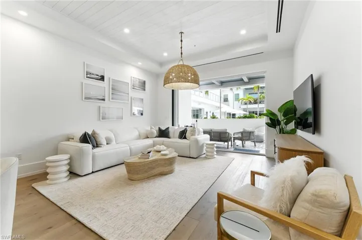Living room with light wood floors, recessed lighting, wood ceiling, and a tray ceiling