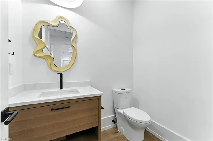 Half bath featuring vanity and wood finished floors just off the entry