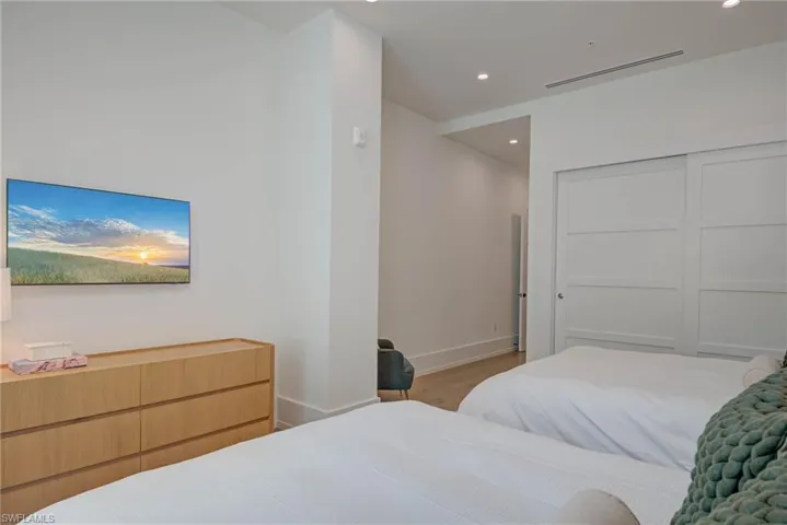 Bedroom with wood finished floors, recessed lighting, and a closet