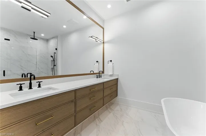 Bathroom featuring a marble finish shower, double vanity, marble finish floors, a freestanding tub, and recessed lighting