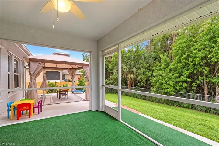 Screened patio with ceiling fan, artificial turf flooring, and private backyard access