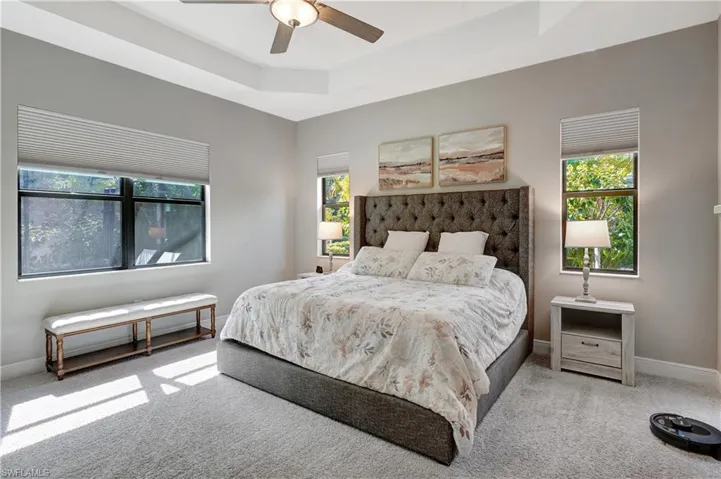 Bedroom with carpet floors, baseboards, a tray ceiling, and ceiling fan