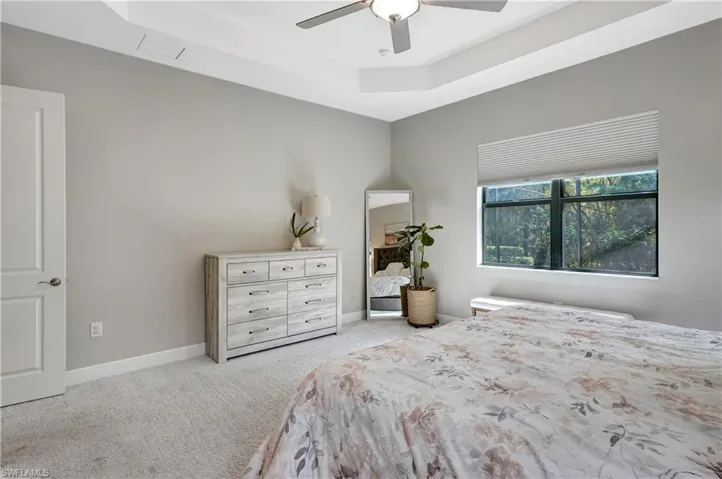 Bedroom with carpet, ceiling fan, a raised ceiling, and baseboards