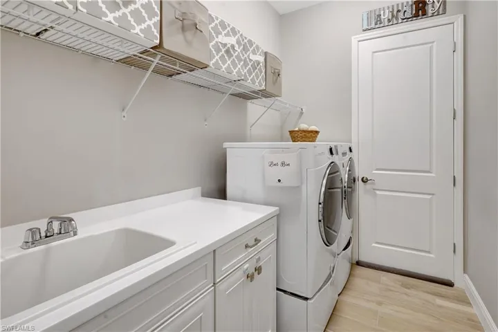 Custom laundry area with built in cabinet space, sink, Wi-Fi capable washer and dryer with storage pedestals