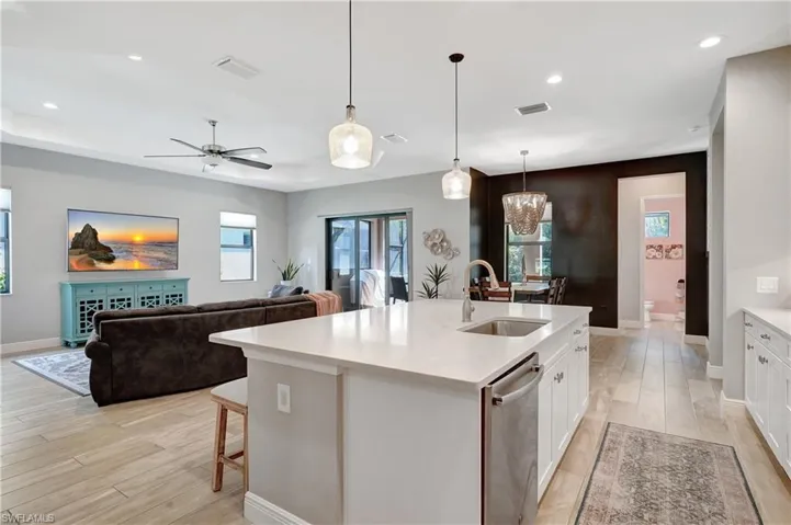 Kitchen featuring a center island with sink, light quartz countertops, stainless steel dishwasher, open floor plan