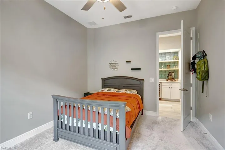 Second bedroom featuring light colored carpet, ceiling fan, and baseboards