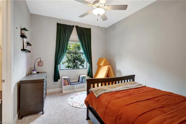 Second bedroom featuring light colored carpet, ceiling fan, and baseboards
