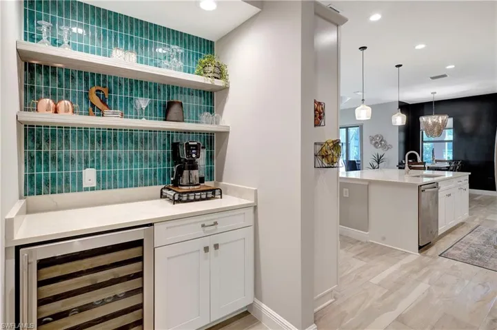 Coffee wine bar featuring built in cabinetry and wine cooler adjacent to open concept gourmet kitchen