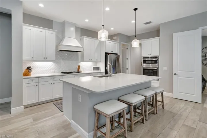 Gourmet kitchen with upgraded stainless steel natural gas appliances, including a range, oven tower, and overhead exhaust hood
