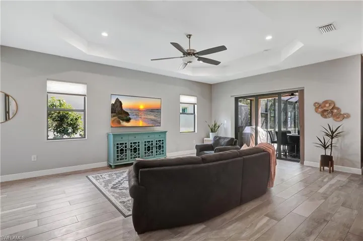Living room featuring light wood-type flooring, plenty of natural light, visible vents, and a tray ceiling