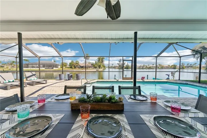 Pool featuring a water view, a jacuzzi, a patio, outdoor dining area, and a lanai