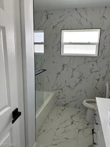 Full bath with vanity, light marble finish floors, and bathing tub / shower combination