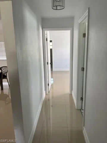 Hallway with baseboards and light tile patterned floors