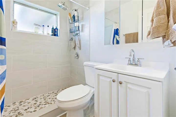 Bathroom with curtained shower, toilet, and vanity