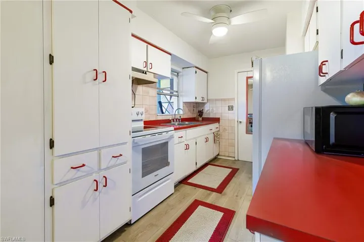 Kitchen featuring light hardwood / wood-style flooring, white electric range, backsplash, ceiling fan, and white cabinetry