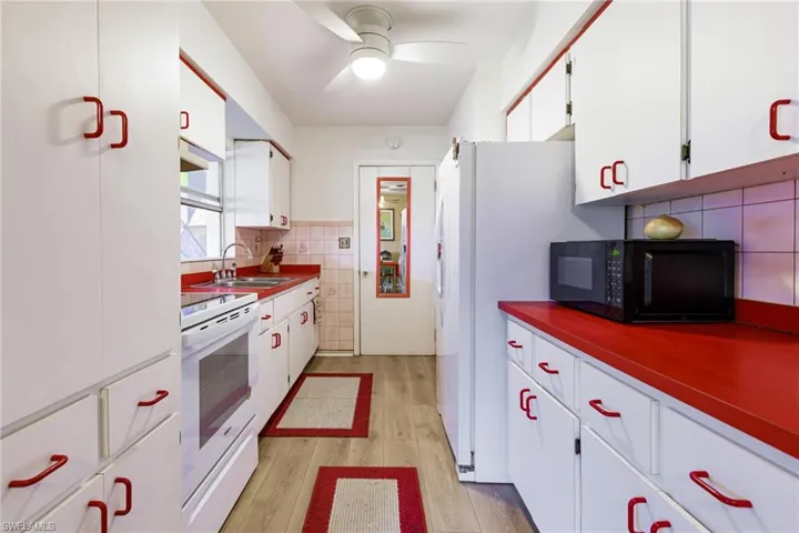 Kitchen with ceiling fan, light hardwood / wood-style flooring, white stove, sink, and white cabinets